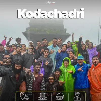 A large group celebrating at the top of Kodachadri, clad in raincoats. This trek is especially popular during the monsoon for its misty and magical atmosphere.
