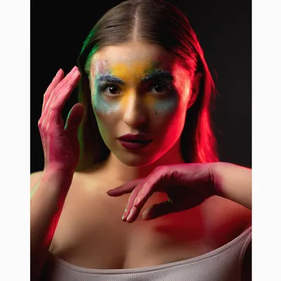A creative beauty portrait using colorful powders and dramatic red and green lighting. This kind of experimental shoot is perfect for beauty editorials or artistic portfolios.