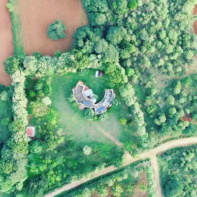 An aerial drone shot of the 18-year-old farmhouse project in Nelamangala. This perspective truly shows how the structure is cradled by nature. The surrounding ring of trees, which I planned from the beginning, has now matured to provide a natural privacy screen and a habitat for local wildlife.