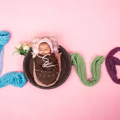 A creative and adorable newborn setup spelling out the word 'LOVE' with soft fabrics. This shot is a beautiful way to celebrate the new love in your family.