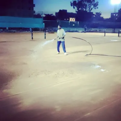 Our ground staff performing nightly watering of the clay courts, a crucial step in maintaining their quality for high-performance tennis.