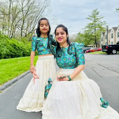 A mother and daughter duo looking lovely in their matching custom lehengas. This view shows how the coordinated teal printed blouses and cream chikankari skirts create a harmonious and stylish look.