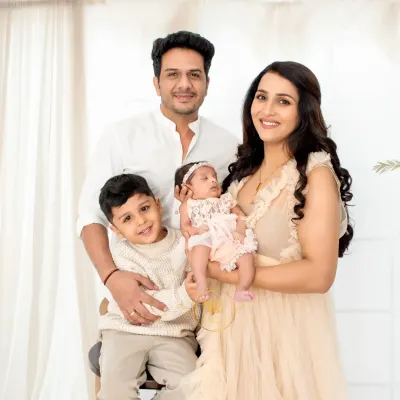 A beautiful family portrait of four. The parents and older brother look lovingly at the new baby girl, capturing a perfect family moment.