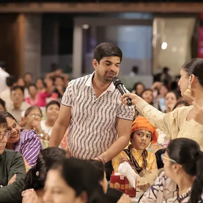 Handing the microphone to a guest in the audience. I believe in giving everyone a chance to share their wishes and stories, making the event more interactive.