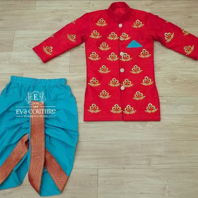 A smart red sherwani-style kurta with all-over gold embroidery. It's paired with a bright turquoise dhoti for a striking contrast.
