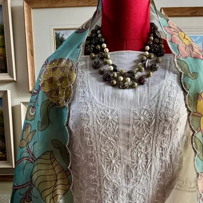 A classic off-white Chikankari suit is elevated by a stunning, hand-painted Srikalahasti Kalamkari organza dupatta. This image, styled with a necklace, shows the perfect harmony between the two crafts.