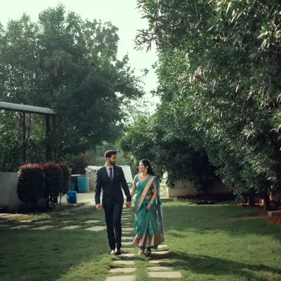 A candid moment of a couple walking hand-in-hand through a garden, lost in their own world.