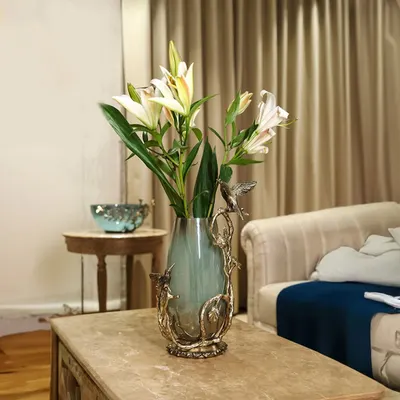 A vase that does not just hold flowers, it holds stories. With sculpted birds dancing around hand-blown glass, this centerpiece brings art and nature together on your coffee table, creating a scene of whimsical elegance.
