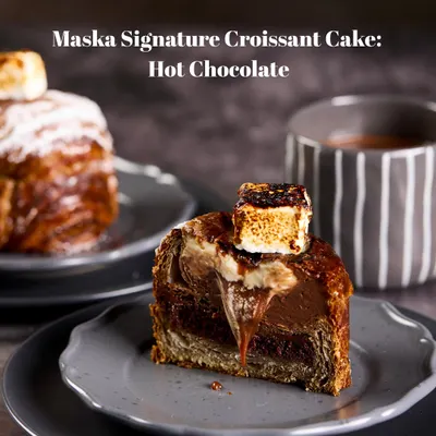 Our Signature Hot Chocolate Croissant Cake is pure indulgence. A buttery croissant holds a rich chocolate cake, salted caramel, and chocolate mousse, all topped with a torched marshmallow for that campfire hot chocolate feel.
