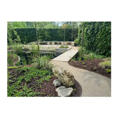 A view of our completed 'Devrai' garden in France, showing the harmony between the stone pathway, lush groundcover, and the tranquil water body. The design invites visitors to walk through a curated natural environment.