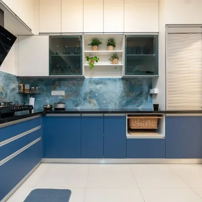 A stunning L-shaped kitchen featuring bold blue base cabinets and crisp white overheads. The design is elevated by a striking blue marble-patterned backsplash, creating a cohesive and dramatic look.