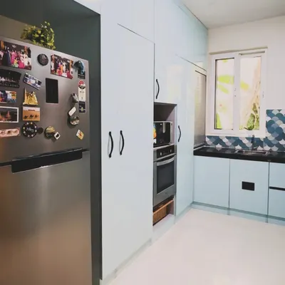 This U-shaped kitchen is brought to life with beautiful pastel blue cabinets. The design includes a tall unit with an integrated oven and microwave, showcasing how color can be combined with complete functionality.