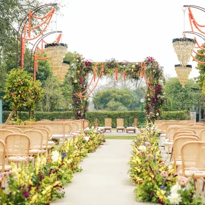 A walk down the aisle should feel like a dream. We lined this garden path with abundant blooms and hung elegant chandeliers from floral arches, creating a charming and luxurious entrance for the bride.