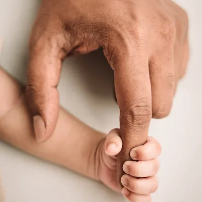 The tiniest hand wrapped around dad's finger. This iconic shot shows the immediate bond and the incredible smallness of your newborn.