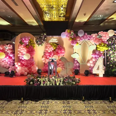 A whimsical and elaborate stage for a fourth birthday party. This bunny and butterfly themed decor is filled with pink balloon clouds, large prop bunnies, a hot air balloon cutout, and a light-up number '4'.