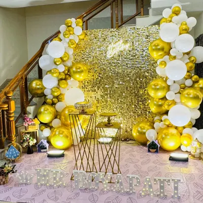 A glamorous gold and white theme featuring a full gold sequin backdrop, framed by a balloon arch.
