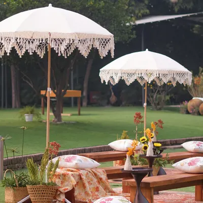A perfect picnic-style setup for a Mehendi. The combination of rustic benches, bohemian umbrellas, and colorful textiles creates a relaxed and chic vibe.