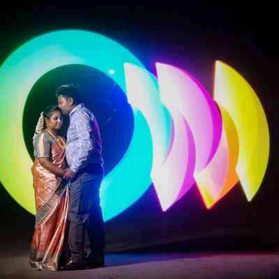 A unique couple portrait created with light painting. I used a special tool to draw these vibrant, abstract shapes of light around the couple in a dark setting, resulting in a magical and futuristic image.