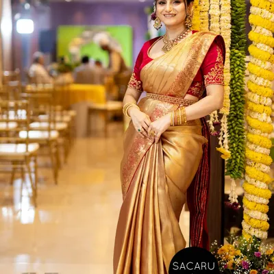 Our radiant client Anusha, celebrating a special family occasion in a custom cherry red satin blouse and a lustrous gold Kanjeevaram saree.