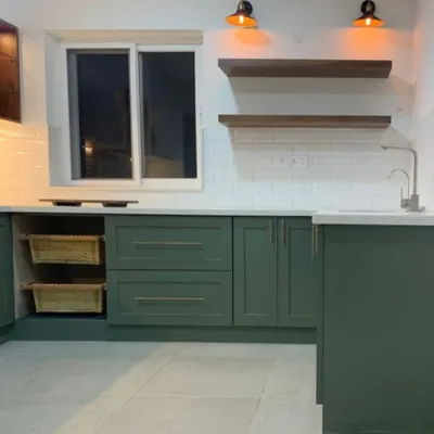 This kitchen doesn’t just cook—it judges your takeout habits and still makes you feel at home. A beautiful sage green kitchen with open shelving and warm lighting.
