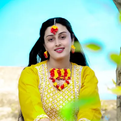 A beautiful portrait of the bride-to-be during her mehndi or haldi ceremony, adorned with floral jewelry. The bright yellow of her outfit is full of festive energy.