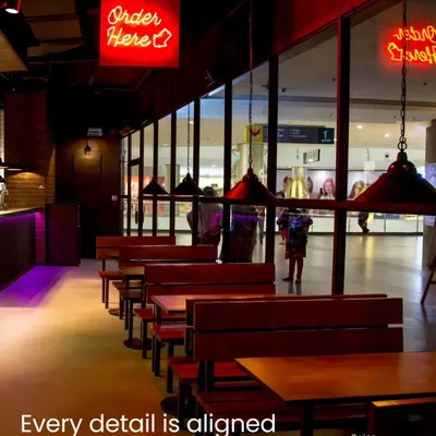 In a QSR, every detail must align with the brand's identity and optimize the customer journey. The 'Order Here' neon sign and organized seating plan in this Taco Bell outlet are designed for clarity and efficient flow, enhancing the fast-casual dining experience.