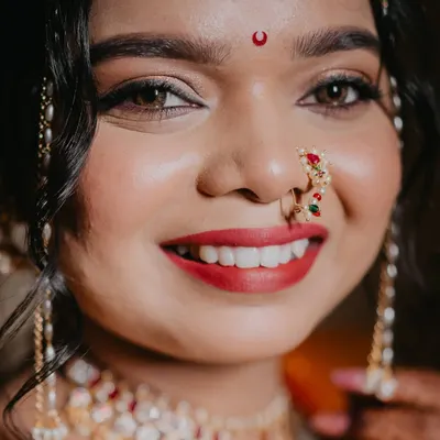 A close-up of this stunning Maharashtrian bride. Her radiant smile, classic red lip, and traditional jewelry come together for a breathtaking look. The airbrush makeup ensures a flawless finish.