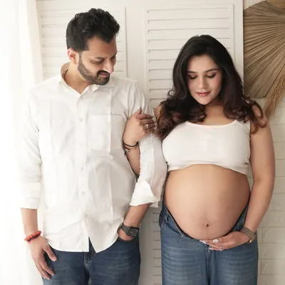 A relaxed and modern couple's portrait. The casual white tops and jeans create a comfortable and authentic feel for this studio maternity shoot.
