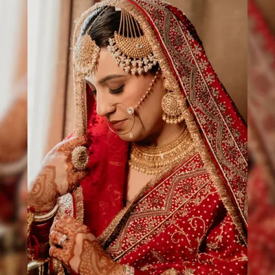 A stunning close-up of our Punjabi bride, Arsh. This portrait highlights her magnificent jewelry, the intricate details of her red bridal lehenga, and her serene expression on her wedding day.