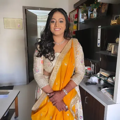 A beautiful client ready for her engagement. Her makeup is soft and glowing, paired with a yellow and white lehenga and loose curls.