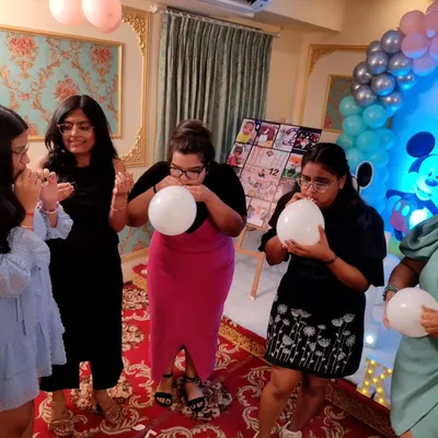 Guests participating in a fun balloon-blowing race at a birthday party. These simple but energetic games are perfect for getting everyone laughing and competing.