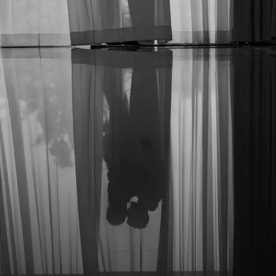 A stolen moment behind the curtains. This artistic reflection shot captures the couple in a quiet, intimate embrace before the whirlwind of the day begins, a secret memory just for them.