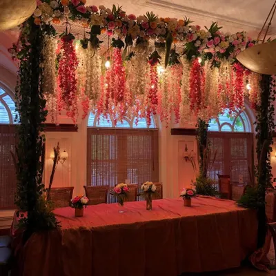 A beautifully decorated head table for a wedding dinner. We created a stunning overhead installation with hanging wisteria and other flowers, creating an intimate and luxurious dining experience.