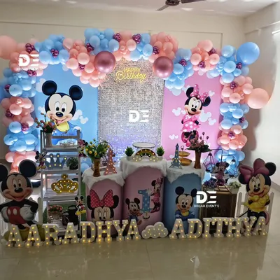 A perfect theme for boy-girl twins: Mickey and Minnie Mouse! This setup for Aaradhya and Adithya's first birthday features a pink side for Minnie and a blue side for Mickey, beautifully united in the middle.