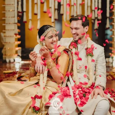 A beautiful moment of love and laughter between the bride and groom, showered with rose petals during their traditional wedding ceremony. These are the moments we live for.