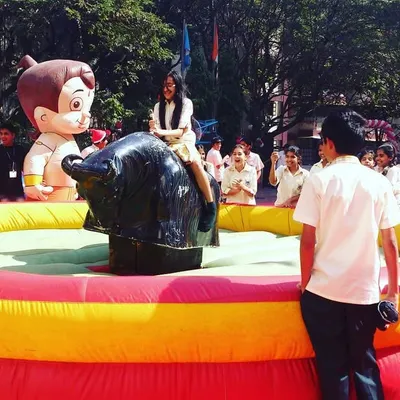 The mechanical bull is one of our premier attractions for large events, seen here at a school fair. It provides a safe yet exhilarating challenge that draws a large crowd and creates a lively atmosphere.