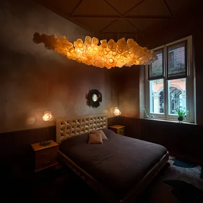 The Bocci 100 series hangs like a luminous cloud over a bed in the Bocci Milan Apartment, creating a warm and dreamlike atmosphere. This installation showcases the series' ability to create a powerful, emotional centerpiece in a bedroom setting.