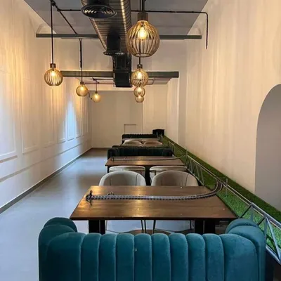 The interior of Kritunga Restaurant, a commercial project we designed. This view shows the linear seating arrangement with plush teal banquettes and a unique conveyor belt system for serving food, creating a memorable dining experience.