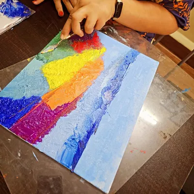 A participant works on her abstract landscape using a palette knife. This technique is perfect for creating rich textures and expressive strokes.