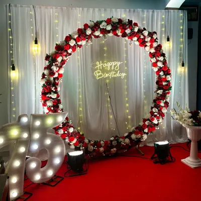 A grand celebration for a 75th birthday, featuring large illuminated marquee numbers and a classic red and white floral ring. The red carpet and spotlights create a VIP experience for the guest of honor.
