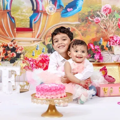 A fun and messy cake smash session to celebrate a first birthday. This little girl and her older brother are enjoying the celebration in a colorful, princess-themed studio setup.