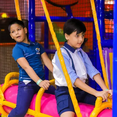 Two boys work together on the swinging log over the ball pit, a fun challenge in our play maze.
