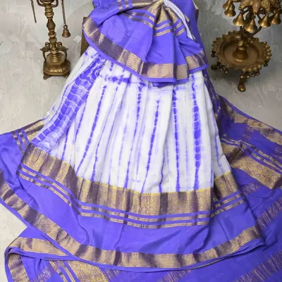 A unique tie-dye silk saree in white and purple with a classic gold border. This is a modern twist on a traditional fabric, perfect for making a style statement.