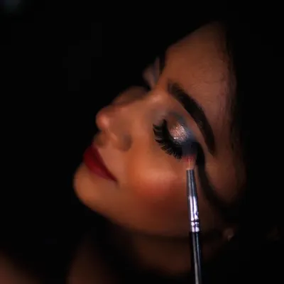 This artistic shot captures a moment of creation. I'm applying a glittery eyeshadow for a reception look, focusing on making the eyes sparkle. It’s all about the details that make a look camera-ready.