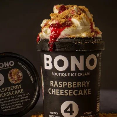 A perfect scoop shot for Bono Boutique Ice Cream. The styling with crumbled biscuits and raspberry sauce highlights the 'Raspberry Cheesecake' flavor and makes the product look indulgent and ready to eat. This is ideal for social media and product listings.