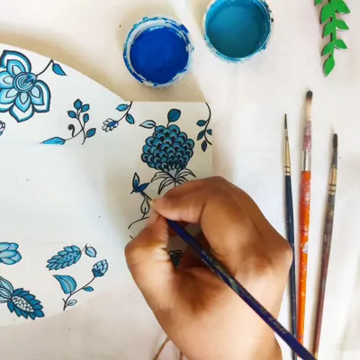 A close-up of my hand at work, painting an intricate blue floral pattern. This kind of detailed work is meditative for me and is perfect for personalizing smaller items like nameplates or keepsake boxes, turning them into cherished family heirlooms.