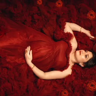 A breathtaking overhead shot of a mother-to-be lying in a sea of red tulle, creating an artistic and romantic vision of motherhood.