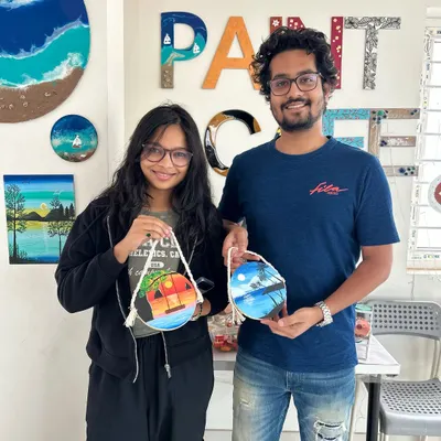 A happy couple showing off the beautiful paintings they created on wooden discs.
