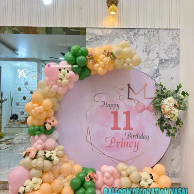 An elegant 11th birthday for Princy with a pastel theme. The round backdrop is framed by a delicate balloon arch in peach, green, and cream, with floral accents.