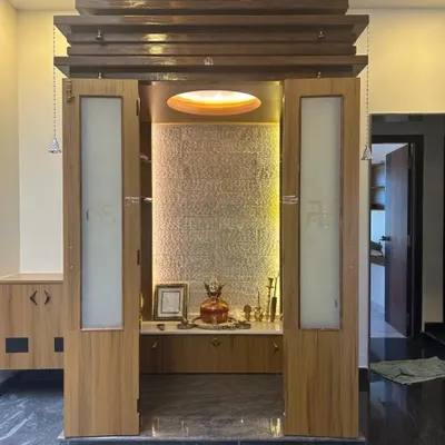 This modern pooja unit is designed to be a spiritual centerpiece in a contemporary home. It features a beautiful textured backdrop, soft lighting, and elegant frosted glass doors with Swastik symbols.